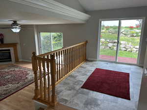 Staircase featuring a fireplace, vaulted ceiling, a ceiling fan, and baseboards