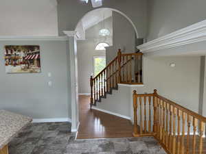 Staircase featuring stone finish floor, baseboards, arched walkways, and high vaulted ceiling