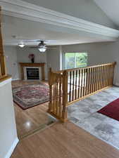 Interior space featuring vaulted ceiling, wood finished floors, ceiling fan, a tiled fireplace, and baseboards