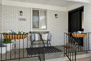 Entrance to property featuring brick siding and a porch