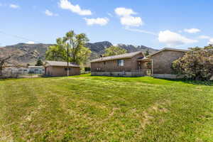 Back of property featuring brick siding, a yard, fence, and a mountain view