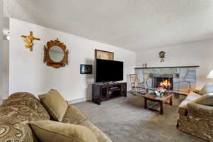 Carpeted living area featuring a fireplace, visible vents, and a textured ceiling