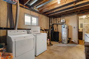 Washroom featuring water heater, washer and clothes dryer, and laundry area