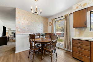 Dining area with light wood-type flooring, plenty of natural light, and an inviting chandelier