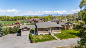 Ranch-style home featuring a front lawn, dirt driveway, an attached garage, a mountain view, and brick siding