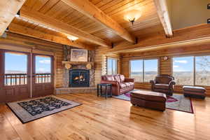 Living room featuring rustic walls, french doors, beamed ceiling, wood ceiling, and hardwood / wood-style flooring