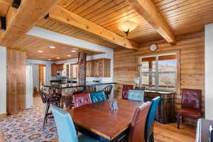 Dining space featuring wood ceiling, recessed lighting, rustic walls, and beamed ceiling