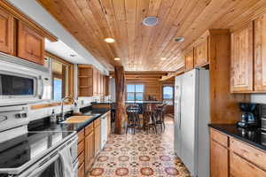 Kitchen with wooden ceiling, a sink, white appliances, and recessed lighting
