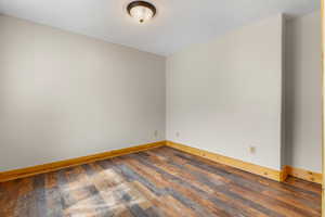 Empty room with baseboards and dark wood-style floors