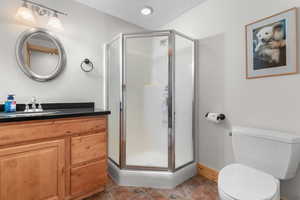 Bathroom featuring toilet, baseboards, vanity, and a stall shower
