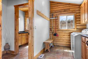 Laundry room with washing machine and dryer, log walls, baseboards, and cabinet space