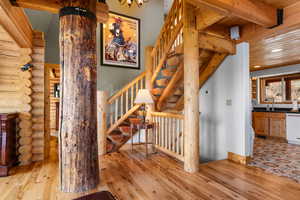 Stairway with hardwood / wood-style flooring, log walls, beam ceiling, and recessed lighting