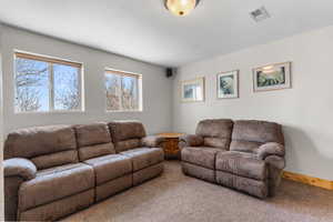 Living room with a textured ceiling, visible vents, carpet flooring, and baseboards