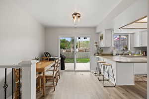 Kitchen with white cabinetry, light wood-style flooring, a breakfast bar, and light countertops