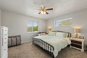 Bedroom featuring a textured ceiling, carpet flooring, baseboards, and a ceiling fan