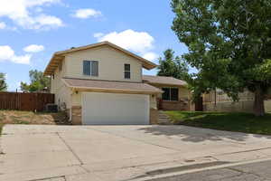 Traditional home featuring brick siding, cooling unit, a garage, and fence
