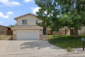 View of front facade with fence, concrete driveway, an attached garage, brick siding, and a front yard