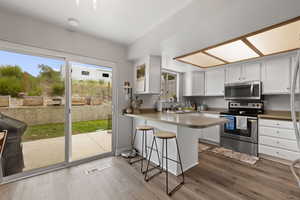 Kitchen featuring stainless steel appliances, a peninsula, a sink, visible vents, and wood finished floors