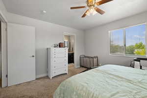 Bedroom featuring a textured ceiling, baseboards, carpet, a ceiling fan, and ensuite bath