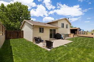Back of house featuring a lawn, a fenced backyard, roof with shingles, and a patio