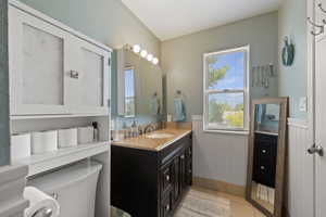 Bathroom with tile patterned flooring, a wainscoted wall, vanity, and toilet