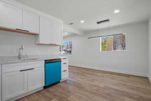 Kitchen featuring white cabinets, a sink, baseboards, recessed lighting, and dishwasher