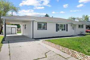 Single story home with a storage shed, an outbuilding, a carport, concrete driveway, and a front yard