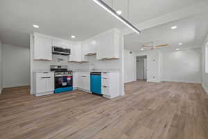 Kitchen with open floor plan, light wood finished floors, light countertops, appliances with stainless steel finishes, and recessed lighting