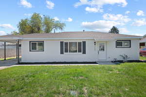 Ranch-style home featuring a front lawn, an attached carport, fence, and a shingled roof