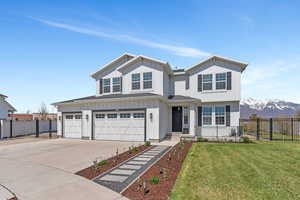 Traditional-style home with fence, a front lawn, board and batten siding, and concrete driveway