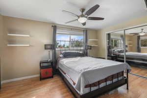 Primary bedroom featuring light wood-type flooring, large closet, a ceiling fan, and baseboards