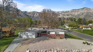 Ranch-style home featuring a garage, brick siding, concrete driveway, and a mountain view