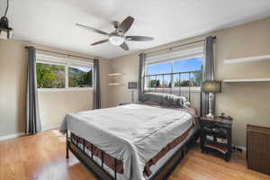 Primary bedroom featuring light wood-type flooring, a ceiling fan, and baseboards