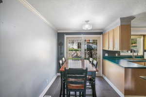 Dining area featuring dark tile patterned floors, crown molding, and baseboards