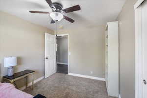 Carpeted bedroom featuring baseboards, a ceiling fan, and a textured ceiling