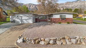 Ranch-style house featuring concrete driveway, brick siding, a mountain view, and a garage
