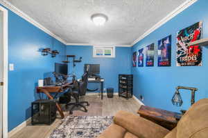 Office space featuring wood finished floors, a textured ceiling, baseboards, and ornamental molding