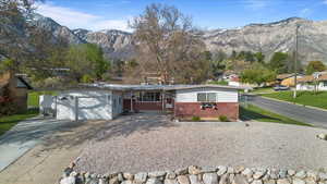 Single story home featuring a mountain view, covered porch, concrete driveway, brick siding, and a garage