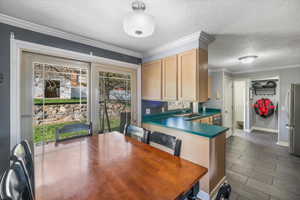 Kitchen featuring stainless steel appliances, light brown cabinetry, a sink, dark countertops, and baseboards