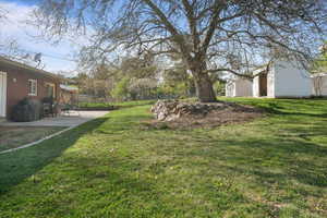 View of yard with an outdoor structure, fence, and a patio