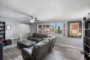 Living area featuring baseboards, wood finished floors, ceiling fan, and ornamental molding
