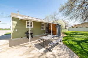 Back of property featuring a yard, a patio, and fence