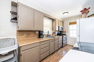 Kitchen with light countertops, gray cabinets, a sink, light wood-style floors, and appliances with stainless steel finishes