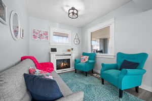 Living area featuring a warm lit fireplace, wood finished floors, and baseboards