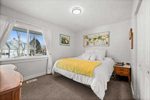 Bedroom with dark carpet, baseboards, and visible vents