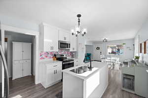 Kitchen with a sink, an inviting chandelier, stainless steel appliances, light countertops, and dark wood-type flooring