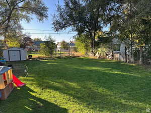 View of yard with fence, an outdoor structure, and a storage shed