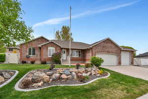 Single story home featuring a gate, concrete driveway, a front lawn, an attached garage, and brick siding
