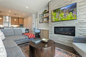 Living area with baseboards, a stone fireplace, wood finished floors, and recessed lighting