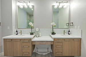 Full bathroom with two vanities, walk in shower, and a sink